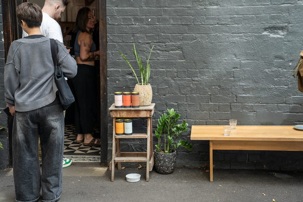 People standing outside Patricia with a small wooden step ladder, a bench, and plants.