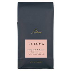 Navy blue recyclable coffee bag, with the Patricia logo in gold. It has a pink label that reads 'La Loma'.