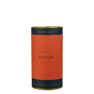 A navy blue cylinder with a red label describes the roasted coffee beans within. 'PATRICIA' and 'TWO HUNDRED GRAMS' are printed in gold foil.